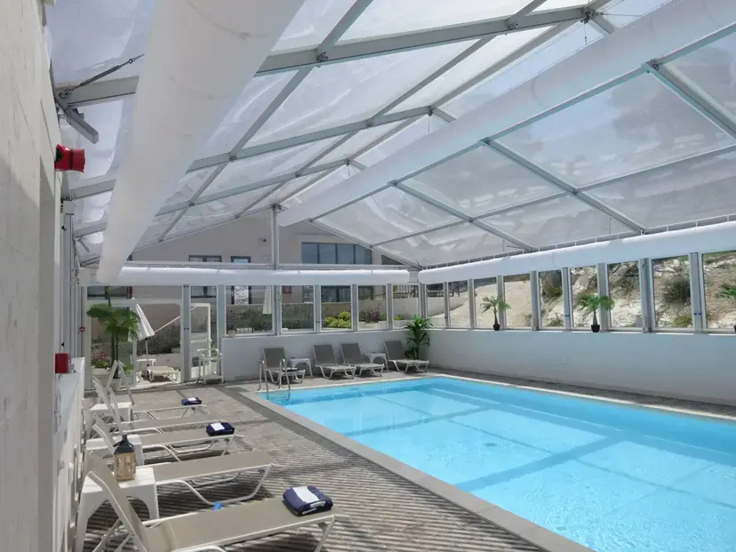 Large A-frame event tent installed over uneven terrain for year-round pool use