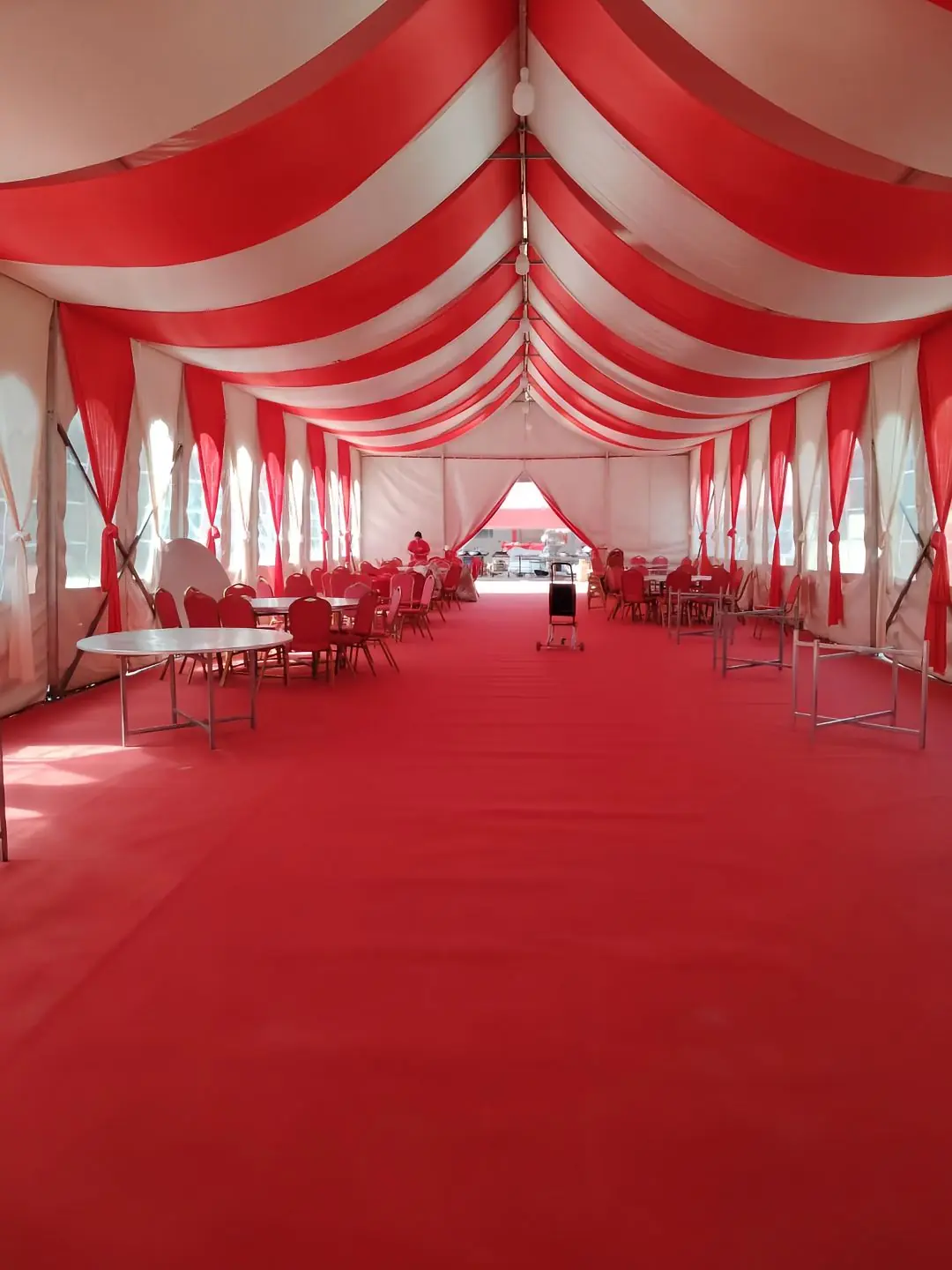 Colorful wedding tent interior decorated with lights, chairs, and red carpet for a grand celebration