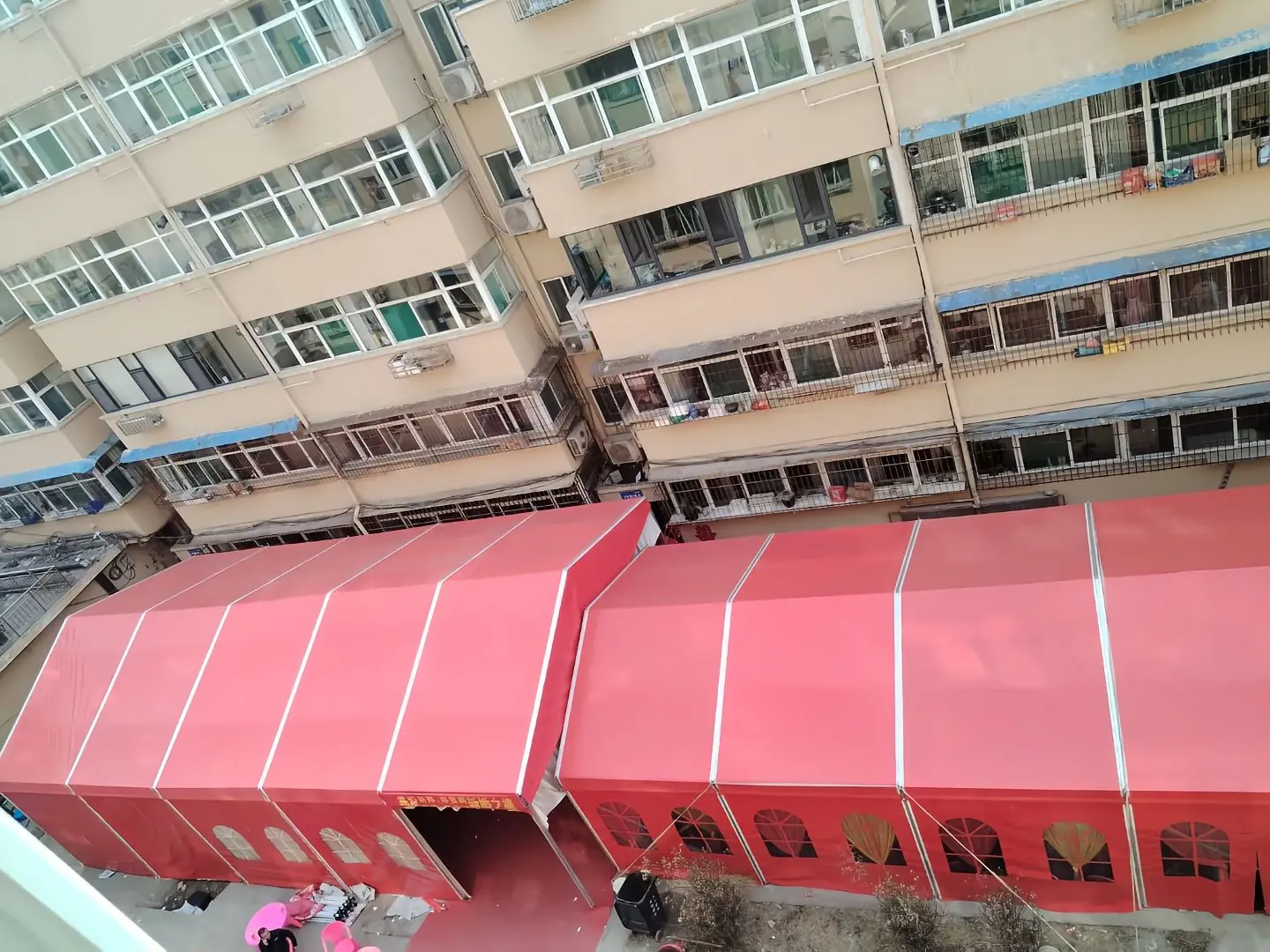 Exterior of 10x45m red and white striped wedding tent set up for an outdoor cultural festival